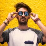 Man in White and Gray Shirt Wearing Sunglasses Against Yellow Wall